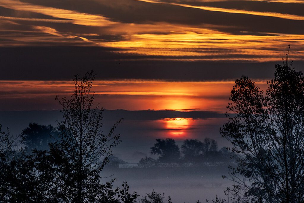 Svitanje u jesensko rano jutro, sa Suncem na horizontu uz malo magle